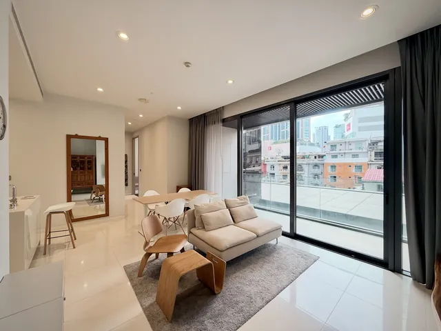 Vittorio Sukhumvit 39 · Unit 2A – Living room with sofa, dining table and floor-to-ceiling sliding doors to the balcony